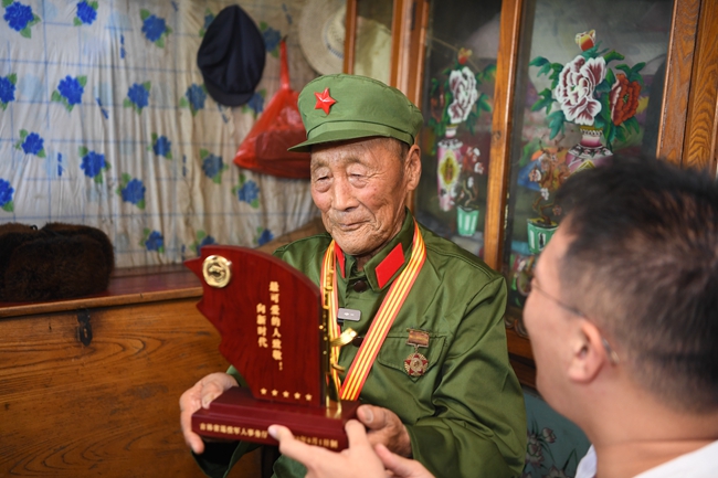 省退役軍人事務廳人員向老兵張俊財贈送榮譽激勵牌。