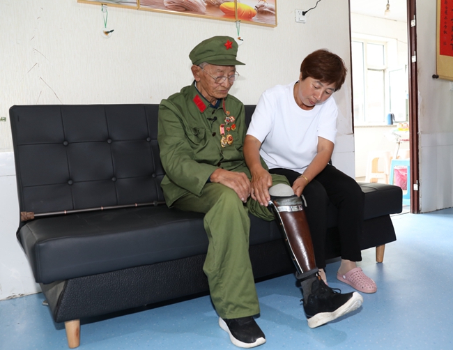 老兵王振余親屬幫助他佩戴假肢。
