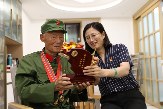 志愿者為老兵安福英贈送榮譽激勵牌。
