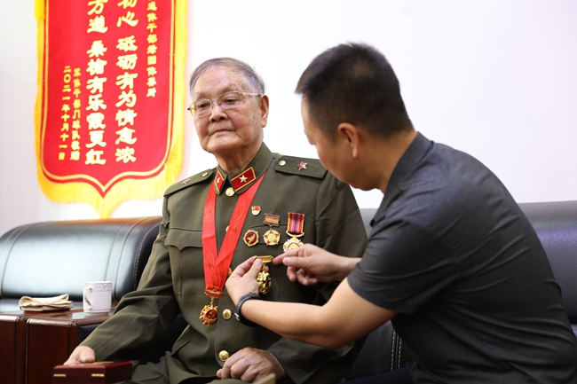 關愛老兵志愿者為老兵汪延開佩戴軍功章。