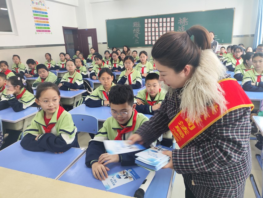 鐵東區司法局工作人員為學生們發送《尊法守法，平安一生》宣傳手冊。