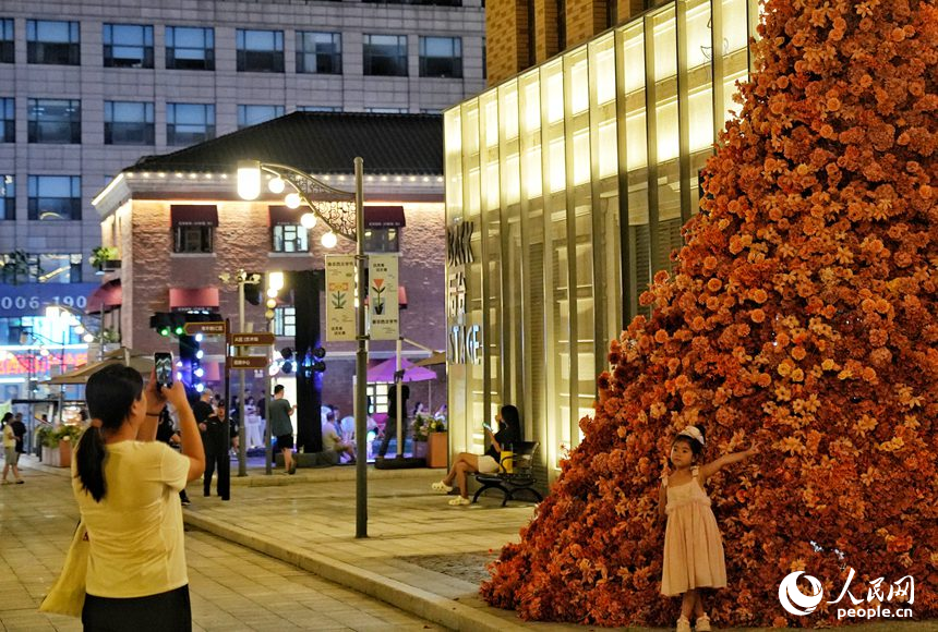 一名小朋友在春京西文旅街區打造的鮮花墻前拍照留念。人民網記者 李洋攝
