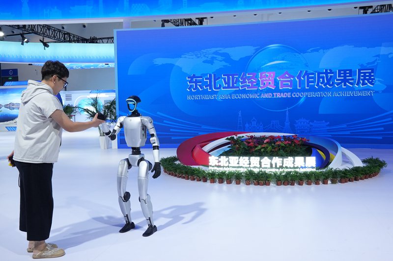 游客在東北亞經貿合作成果展上與機器人握手。人民網記者 李洋攝