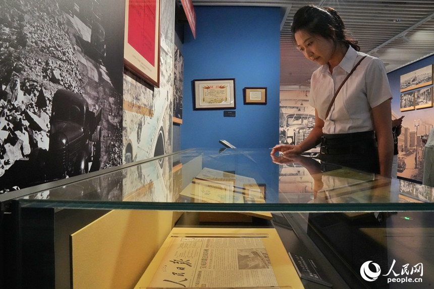 一名觀眾在展區內觀看1956年《人民日報》關于解放牌卡車試制成功的報道。人民網記者 李洋攝