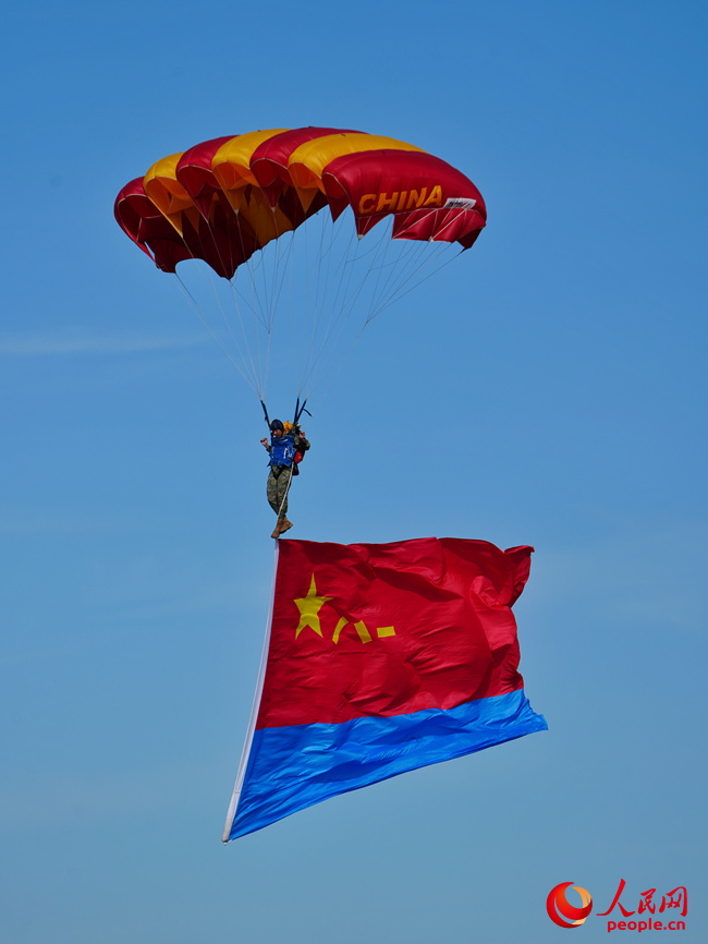 “八一”“藍鷹”跳傘隊攜帶黨旗、國旗、八一軍旗和空軍軍旗先后躍出機艙，而后，多名跳傘