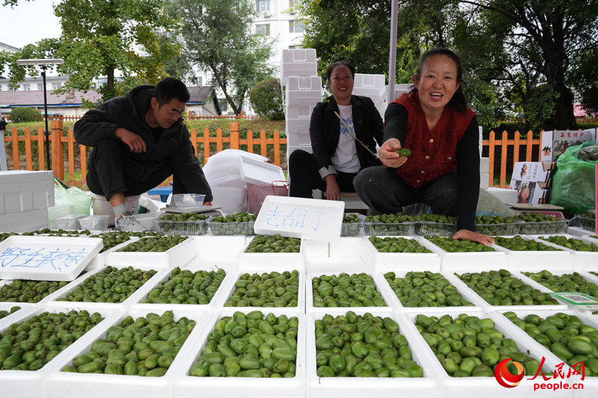 早市上，攤主邀請游客品嘗當地特產軟棗獼猴桃。人民網記者 李洋攝