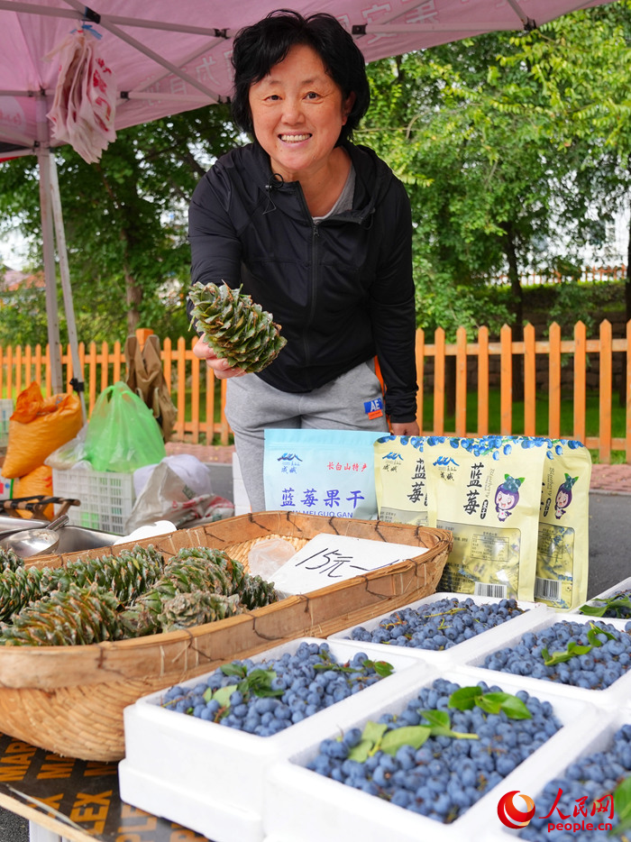 早市上，一名攤主向記者展示當地特產松塔。人民網記者 李洋攝